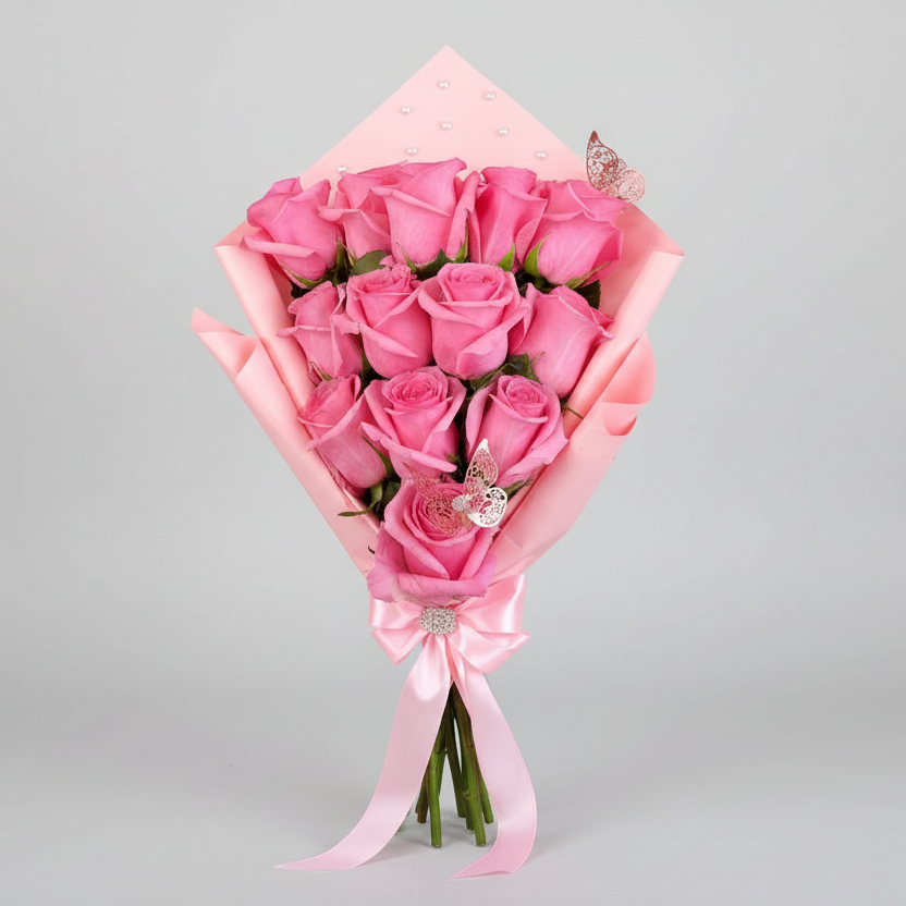 Elegant bouquet of 12 pink roses wrapped in soft pink paper, decorated with delicate butterfly accents and finished with a satin ribbon, available for delivery in Medellín, Colombia.