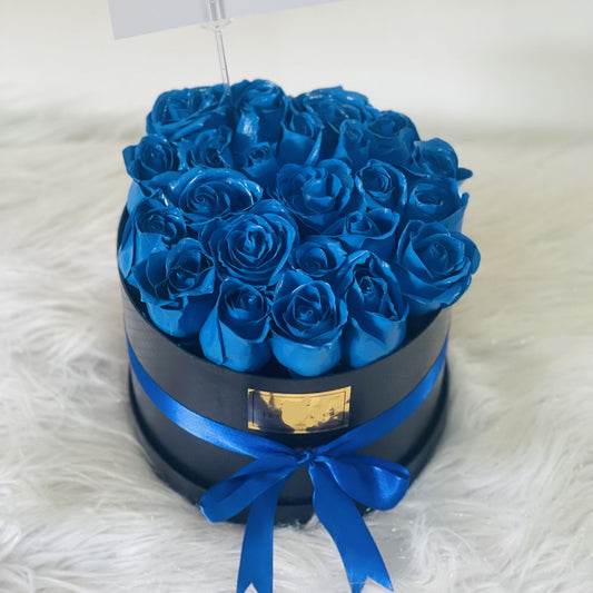 Box of 25 blue roses with a satin ribbon in black packaging – elegant floral gift for men, available for delivery in Medellín.