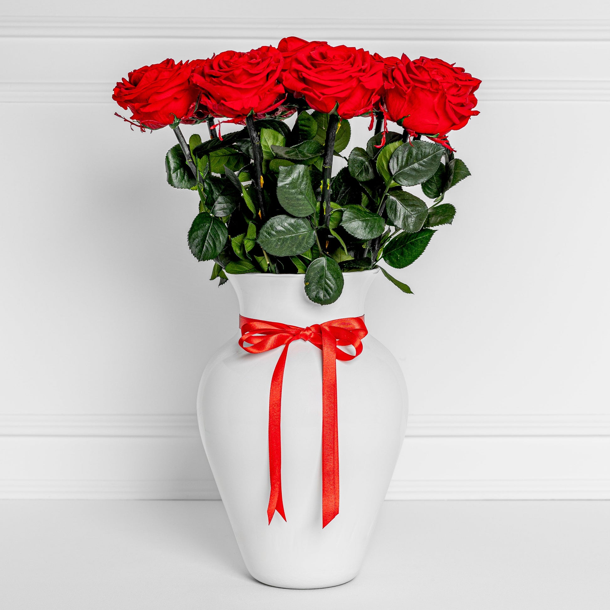 Elegant white vase with 8 preserved red roses and satin ribbon – long-lasting flowers for Medellín same-day delivery.