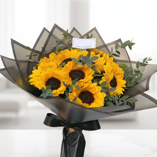 Bouquet of 8 yellow sunflowers with eucalyptus in black Korean paper wrap and black ribbon – Arboletes delivery