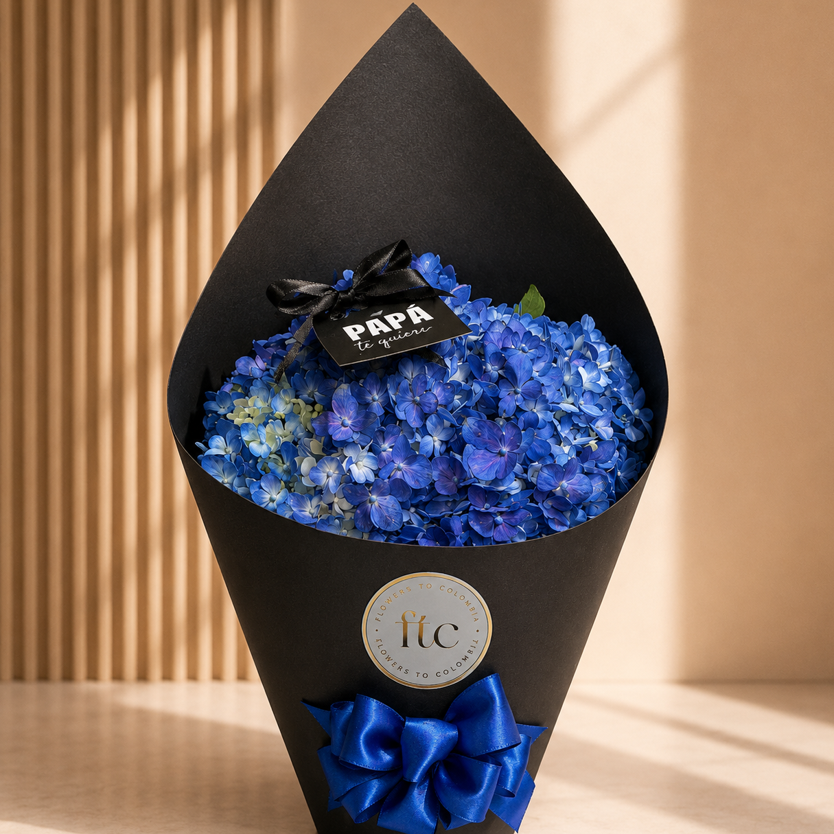 Bouquet of blue flowers wrapped in black paper with a blue bow, against a beige background.