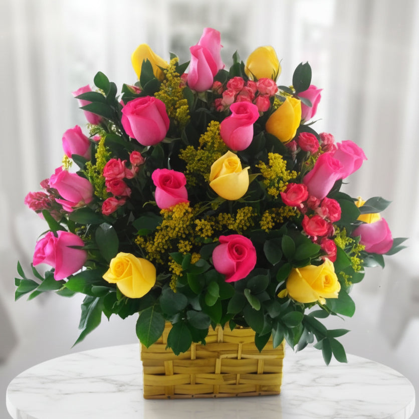 Floral arrangement with yellow and fuchsia roses in a yellow basket, with mini carnations and greenery