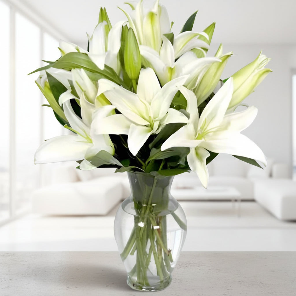 Elegant white lilies in glass vase for sympathy and condolence flower delivery in Colombia