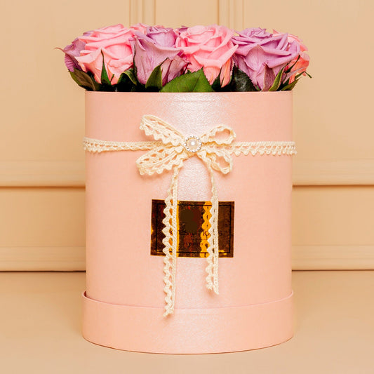 Elegant round pink box with preserved lilac and pink roses, decorated with lace and pearl ribbon, ideal for Mother’s Day delivery in Medellín.