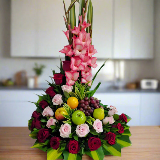 Elegant floral arrangement with red and pink roses, gladiolus, and fresh seasonal fruits like apples, oranges, and grapes. Perfect for delivery in Cartago, Valle
