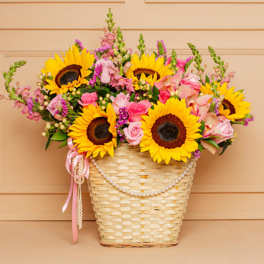 Mother’s Day flower basket with sunflowers, roses, and seasonal blooms in a woven basket with pearl details – Medellín delivery