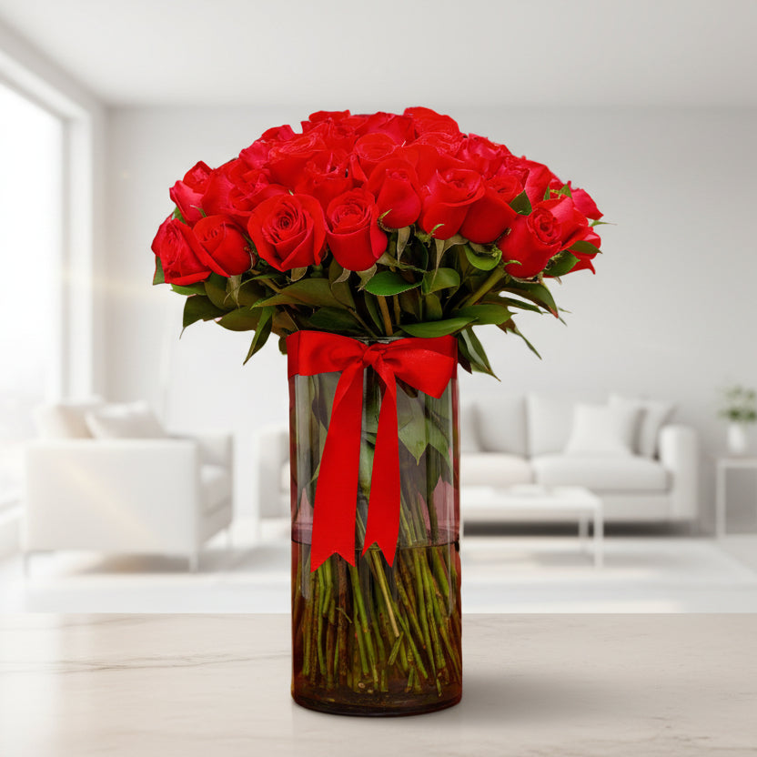 Elegant arrangement of red roses in a glass vase with a red ribbon, perfect for Valentine’s Day in Medellín.