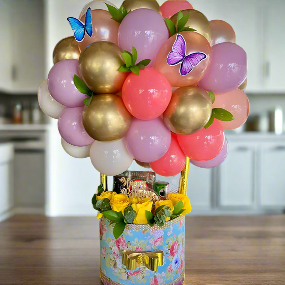 Decorative balloon arrangement with flowers and butterflies on a floral-patterned base.