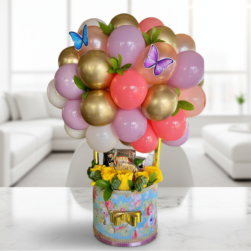 Decorative balloon arrangement with flowers and butterflies on a floral-patterned base.