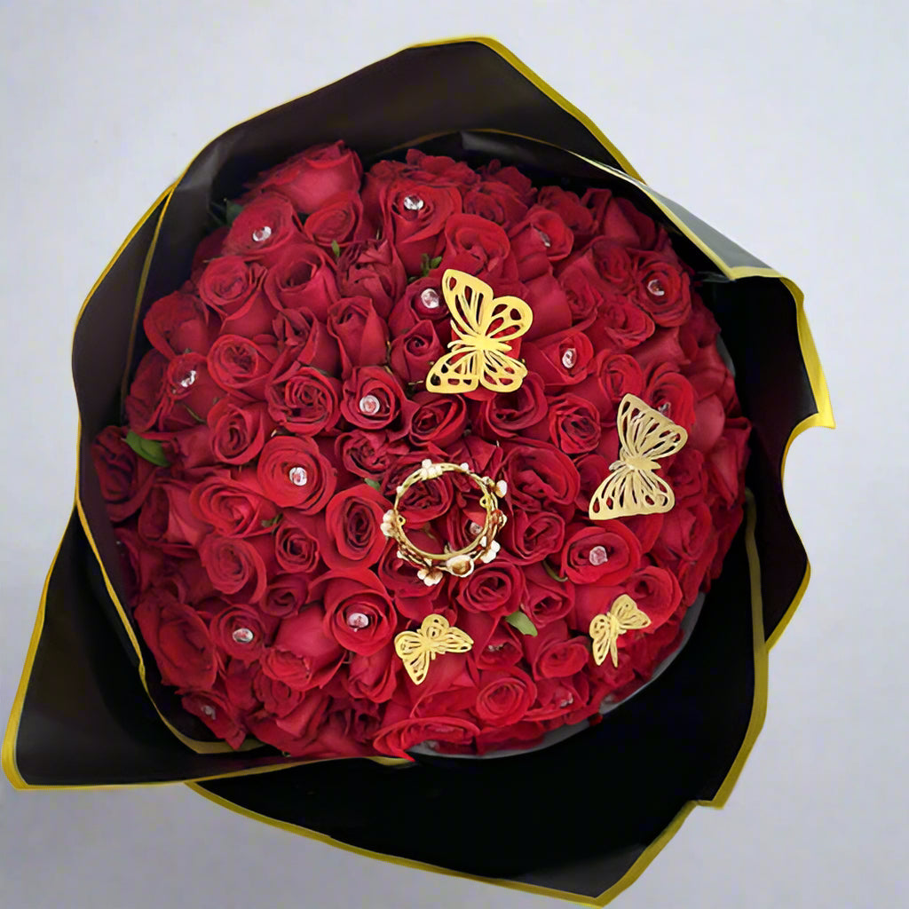 Bouquet of 100 red roses decorated with rhinestones, butterflies, and a crown, wrapped in imported black paper