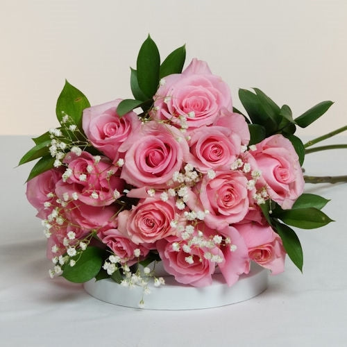 Bouquet of 12 pink roses wrapped in decorative paper with ribbon, available for delivery in all cities of Colombia