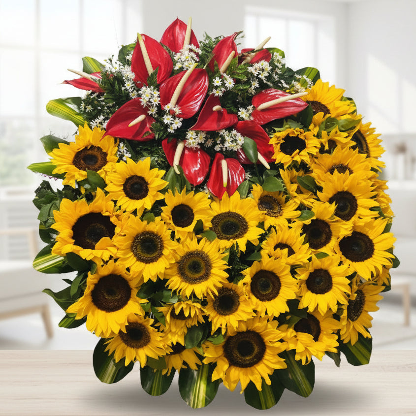Funeral wreath with sunflowers, red anthuriums, and seasonal foliage on a wooden tripod, includes a customizable funeral ribbon, available for delivery in Medellín, Colombia.
