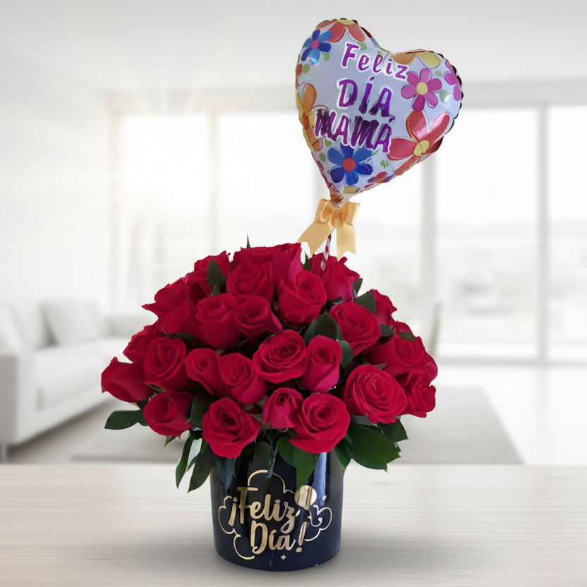 Elegant arrangement of fresh red roses in a black box with 'Feliz Día' in gold lettering, accompanied by a heart-shaped balloon that says 'Feliz Día Mamá.' Perfect gift for Mother's Day with same-day delivery in Cali.