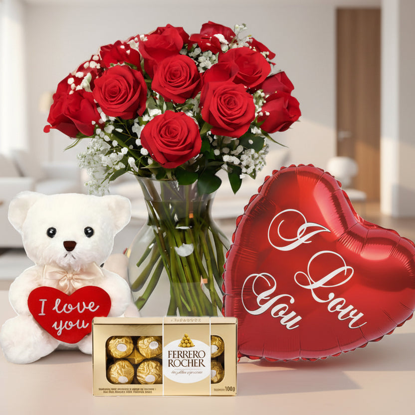 Red roses arrangement in glass vase with teddy bear, I Love You heart balloon, and Ferrero Rocher chocolates, romantic flower delivery in Medellín.