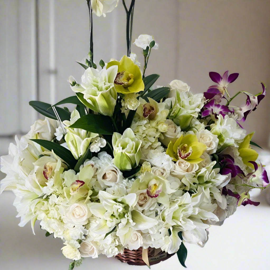 Elegant sympathy arrangement with white orchids, roses, lilies, and white flowers for condolence delivery in Colombia