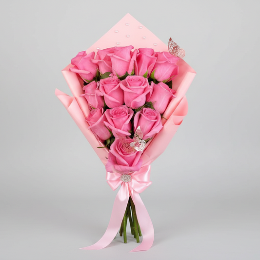 Elegant bouquet of 12 pink roses wrapped in soft pink paper, decorated with delicate butterfly accents and finished with a satin ribbon, available for delivery in Medellín, Colombia.