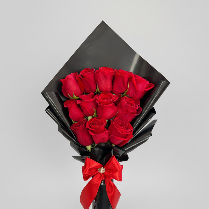 Elegant bouquet of 12 red roses wrapped in premium black Korean-style paper, finished with a red satin bow, perfect for romantic gifting.
