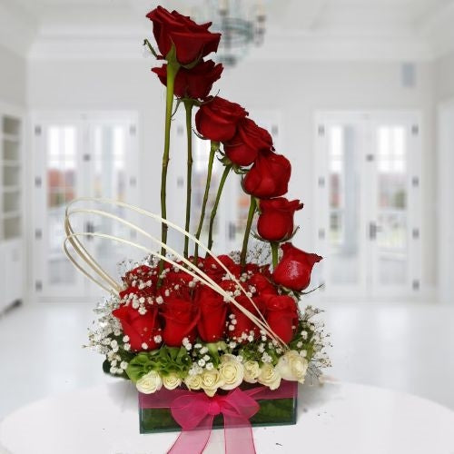 Two dozen red roses un glass vase. .