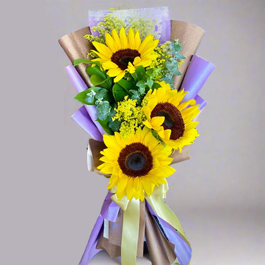 Bouquet of 3 sunflowers with greenery in purple and kraft Korean paper wrap with yellow ribbon – delivery in Arboletes, Antioquia