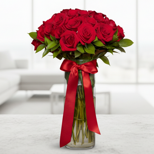 Elegant arrangement of 50 fresh red roses in a clear glass vase with satin ribbon, flower delivery in Medellín.