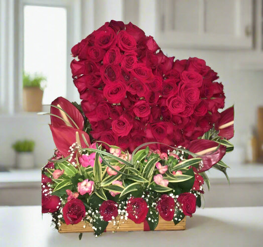 Heart-shaped arrangement with 80 red roses, red anthuriums, pink alstroemerias, and tropical greenery in a rustic wooden box – for delivery in Barranquilla.