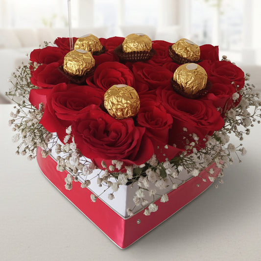 Heart-shaped arrangement of red roses and gold Ferrero Rocher chocolates on a white background