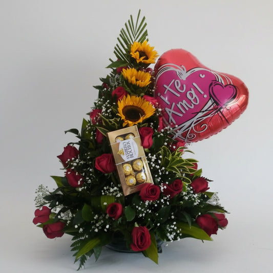 Floral arrangement with red roses, sunflowers, and a Ferrero Rocher chocolate box, accompanied by a heart-shaped balloon with 'Feliz Cumpleaños!' text.