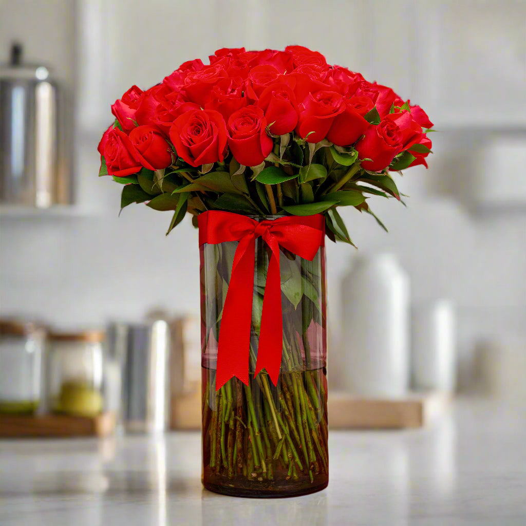 Elegant arrangement of red roses in a glass vase with a red ribbon, perfect for Valentine’s Day in Medellín.
