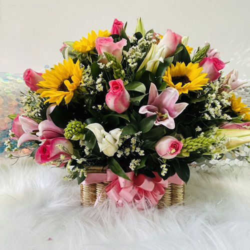Beautiful wicker basket with pink roses, sunflowers, and lilies, available for delivery in Medellín and Cali