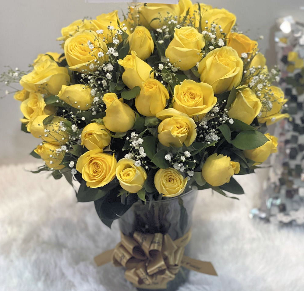 Elegant glass vase arrangement of 45 yellow roses with gypsophila and ruscus, tied with a fabric ribbon, available across Colombia