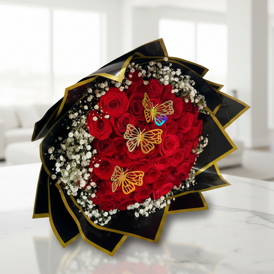 Heart-shaped bouquet of red roses decorated with baby’s breath and golden butterfly accents, ideal for romantic flower delivery in Bucaramanga, Colombia.