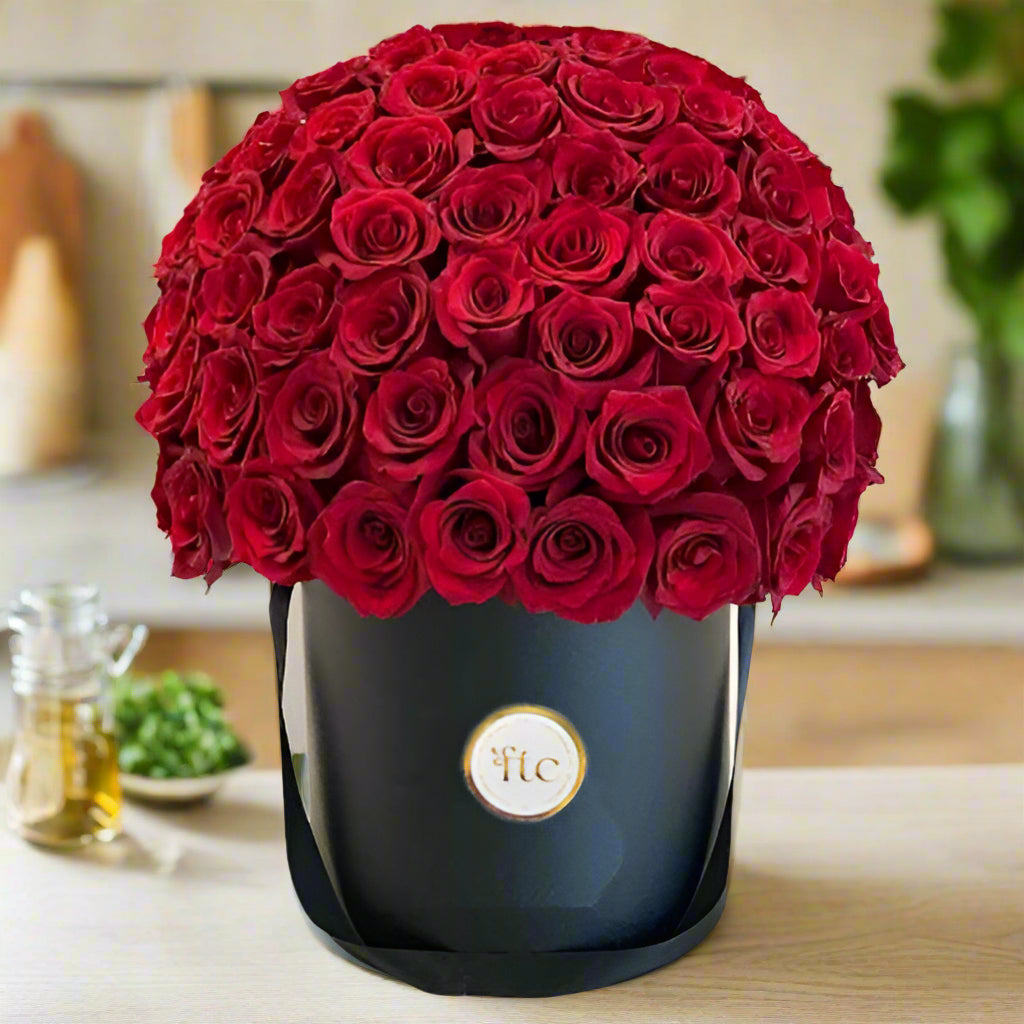 Luxurious black hatbox filled with premium red roses, perfect for romantic occasions like anniversaries and Valentine's Day. Available for delivery in Cali.