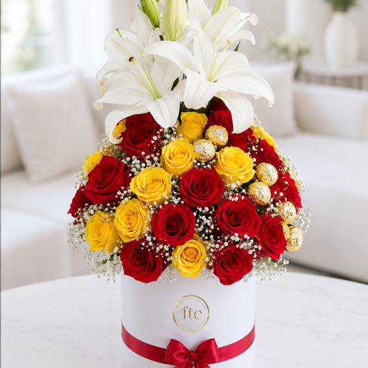 Luxury flower box with white lilies, premium red and yellow roses, Ferrero Rocher chocolates, and baby's breath for same-day flower delivery in Restrepo, Meta.