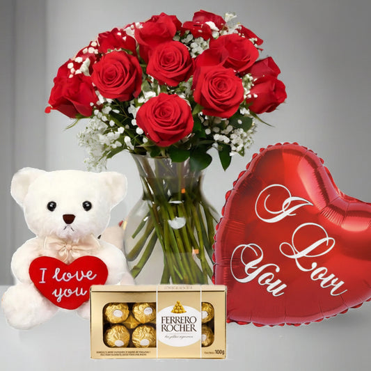Red roses arrangement in glass vase with teddy bear, I Love You heart balloon, and Ferrero Rocher chocolates, romantic flower delivery in Medellín.