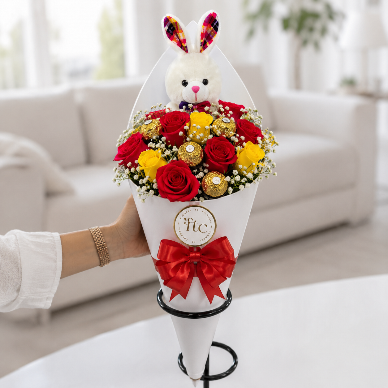 Luxury bouquet with premium red and yellow roses, Ferrero Rocher chocolates, baby's breath, and a plush bunny in an elegant cone wrap for same-day flower delivery in Restrepo, Meta.