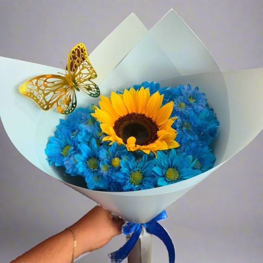 Bouquet with sunflower surrounded by blue daisies, gold butterfly, and blue ribbon – Acacías, Meta