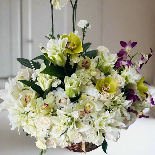 Elegant sympathy arrangement with white orchids, roses, lilies, and white flowers for condolence delivery in Colombia